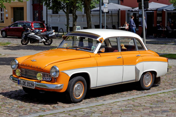 View of an old orange-white classic car, Wartburg 312, in a very good condition, seen in Templin, Brandenburg, Germany on a sunny day. The Wartburg 312 is a german democratic republic vintage car and was build between 1965-1967 in Eisenach. This car was a own brand of the former DDR. Here seen