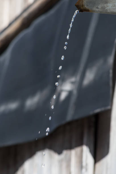 istock water pouring from roof to blue pot 694492270