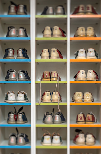 Bowling Alley Rental Shoes in a Shoe Storage Rack. One compartment in the middle is empty.