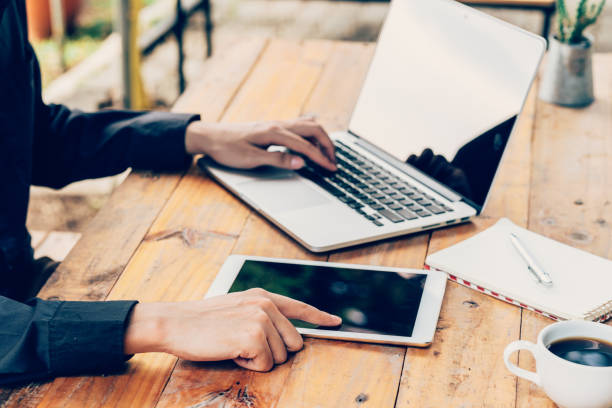 istock Man using tablet and laptop on table in coffee shop. 694499004