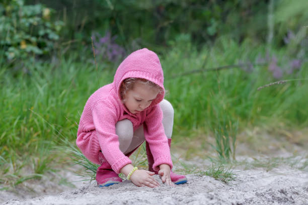 Niña jugando con la arena en el bosque de verano - foto de stock