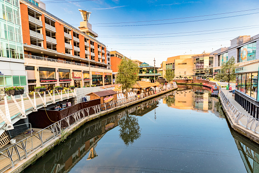 Shops lining both sides of the River Kennet, leading towards the Oracle Shopping Centre, in Reading, Berkshire, England, just before dawn on a summer's morning. Opened in 1999, the Oracle Mall contains well known fashion retailers, bars, restaurants and a cinema.