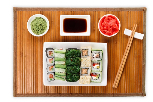 Japanese food restaurant delivery - sushi maki, unagi and roll platter set on mat isolated on white background, above view