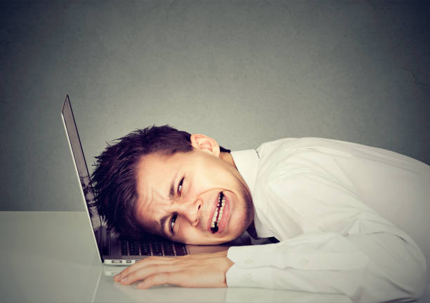 istock desperate business man with head on laptop keyboard 694511730