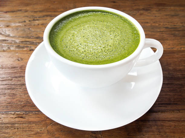istock Hot green tea matcha latte cup with white saucer on wood texture background. 694527150