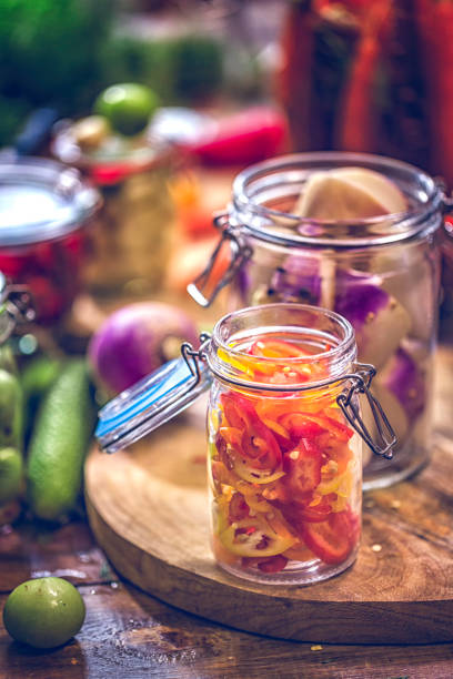 Preserving organic vegetables in jars like carrots, cucumbers, tomatoes, chilis, paprika and radishes.