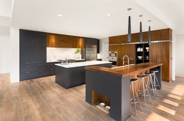 istock beautiful kitchen in new luxury home with two islands, two sinks, pendant lights, oven, range, and hardwood floors 694552526