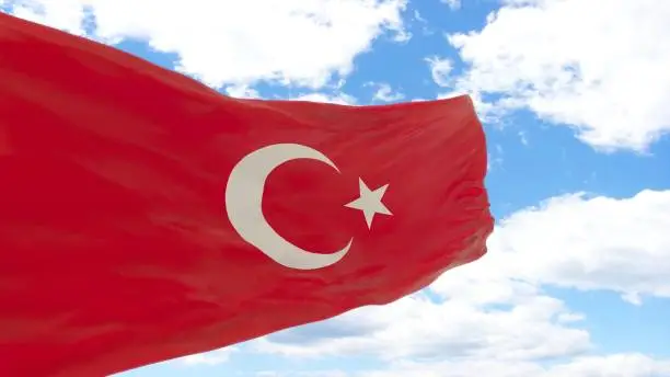 waving flag of Turkey on the blue cloudy sky