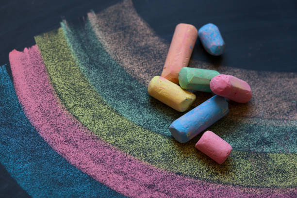 istock Drawing multicolor on dark school chalkboard by colorful chalks, close up 694579016