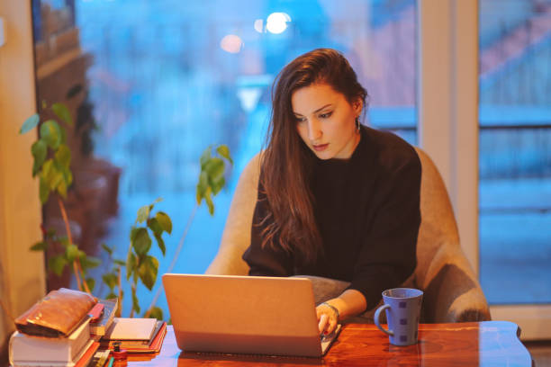 istock Young woman working late at home 694581190