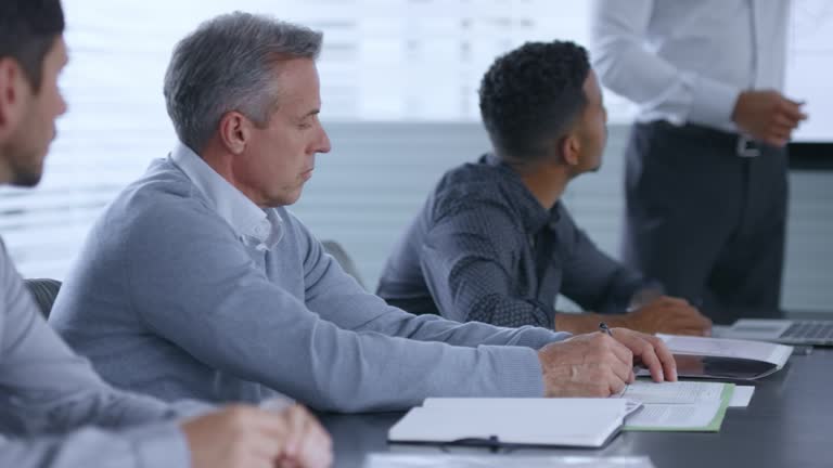 Asian man giving a financial presentation and his colleagues are listening and taking notes