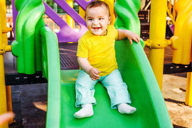 istock Cute boy happily playing on a playground slide 694615934