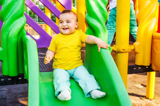 istock Cute boy happily playing on a playground slide 694616032