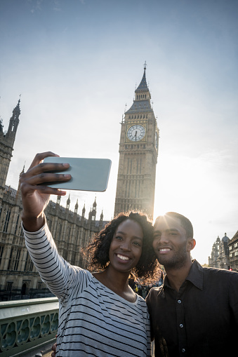 Portrait of a happy African American couple taking a selfie in London with cell phone - lifestyle concepts