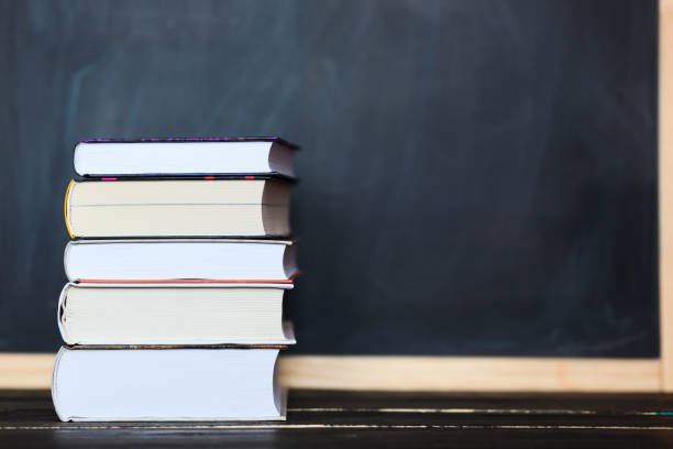 istock Stack of books with chalkboard in background . Space for your text 694619318