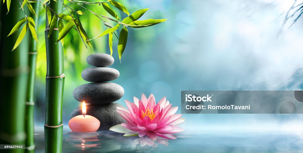 Spa - Natural Alternative Therapy With Massage Stones And Waterlily In Water Candle, black stones and waterlily in pond Zen-like Stock Photo