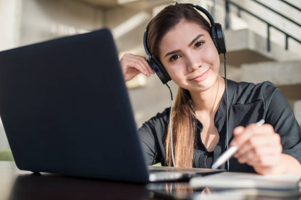 istock Young woman with headphones using laptop 694698128