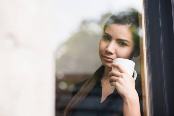 istock Young woman looking out the window 694698152