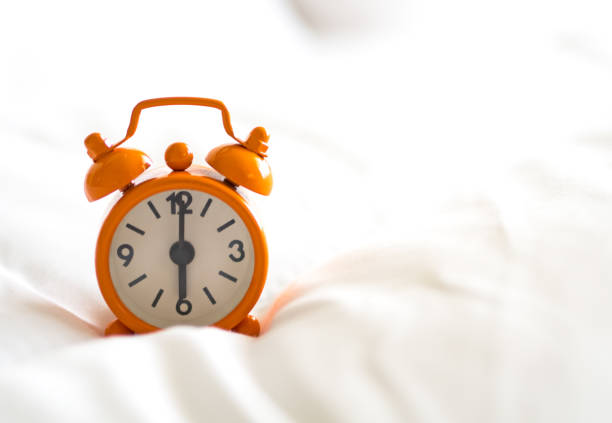 istock Alarm clock on bed in morning with sun light 694700894