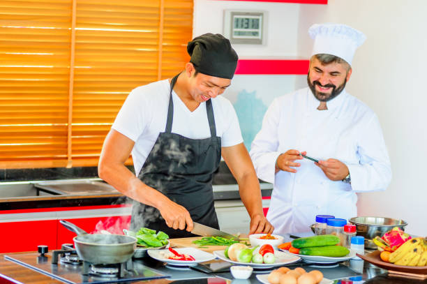 istock Colleagues at work: Thai and European chefs at the kitchen doing Thai food 694703580