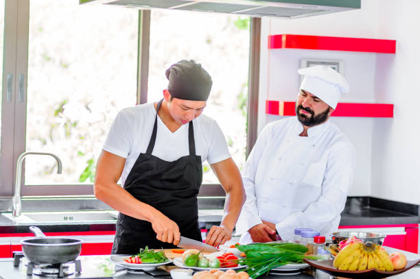 istock Colleagues at work: Thai and European chefs at the kitchen doing Thai food 694703886