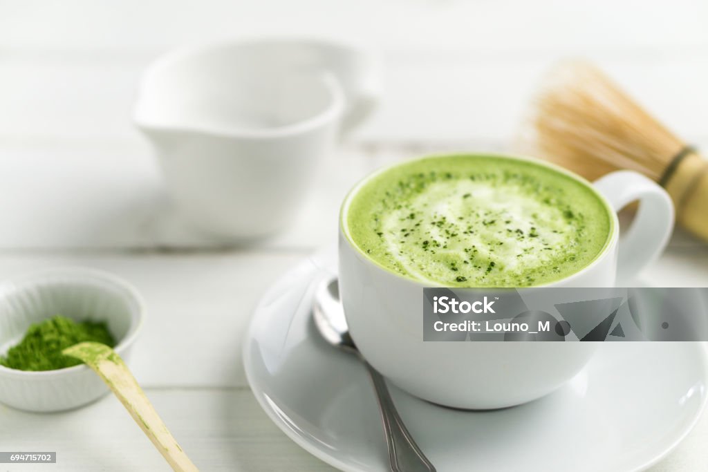 Matcha latte cup close up background blurred. Green tea matcha latte cup on white background. This latte is a delicious way to enjoy the energy boost & healthy benefits of matcha. Matcha is a powder of green tea leaves packed with antioxidants. Matcha Tea Stock Photo