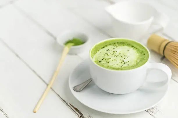Green tea matcha latte cup on white background. This latte is a delicious way to enjoy the energy boost & healthy benefits of matcha. Matcha is a powder of green tea leaves packed with antioxidants.