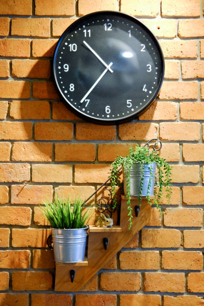 istock Clock and flower pots on red brick wall texture background 694715976