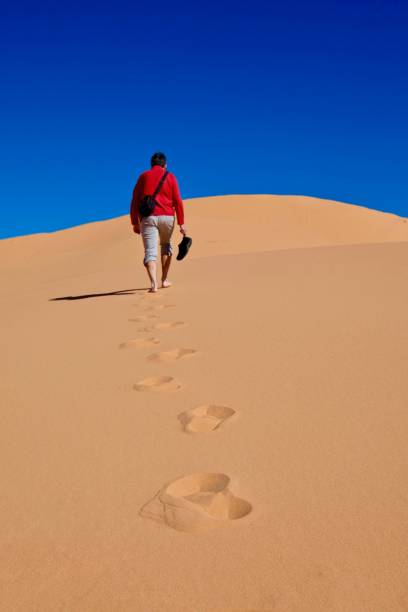 istock Man walking on sand dunes to the sky. 694716506