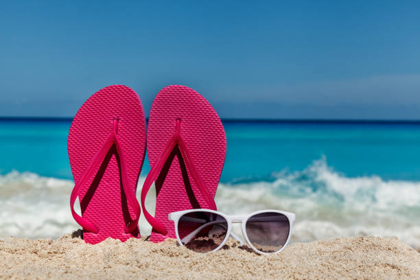 istock Flip flops with sunglasses on the sandy ocean beach in Cancun , Mexico 694719054
