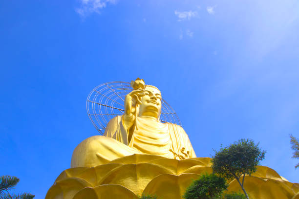istock big golden buddha with blue sky and clouds. 694727940
