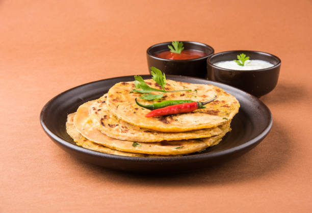 istock Traditional Indian bread - Aloo paratha or aalu parotha, potato stuffed bread. served with tomato ketchup or sauce and curd 694728536