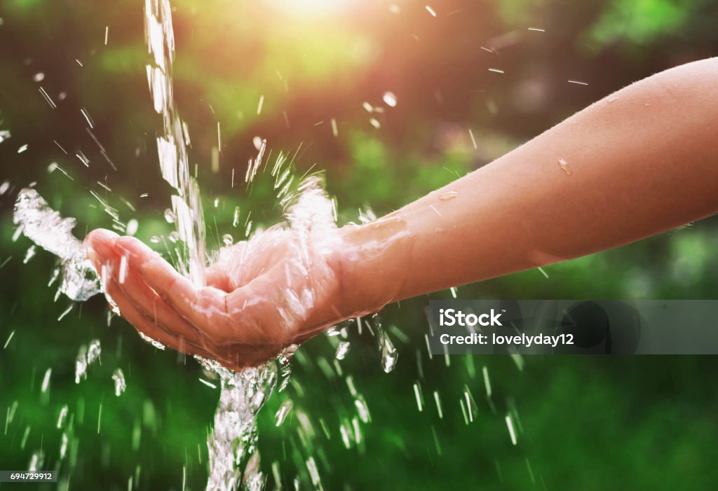 Water pouring splash in hand and nature background with sunshine Water Stock Photo