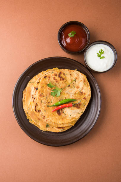 istock Traditional Indian bread - Aloo paratha or aalu parotha, potato stuffed bread. served with tomato ketchup or sauce and curd 694736270