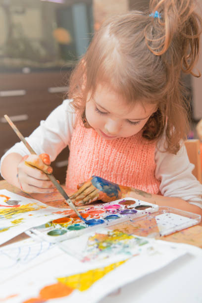 istock girl drawing paints on paper and hands 694740182