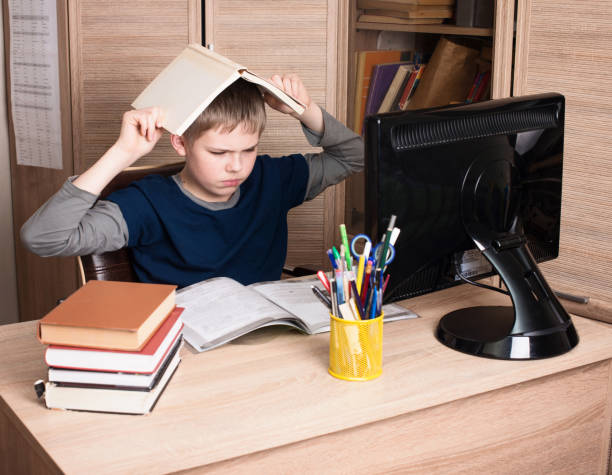 Sad and tired pre teen schoolboy sitting in stress working doing homework in his room. Sad and tired pre teen schoolboy sitting in stress working doing homework in his room. boring homework twelve stock pictures, royalty-free photos & images