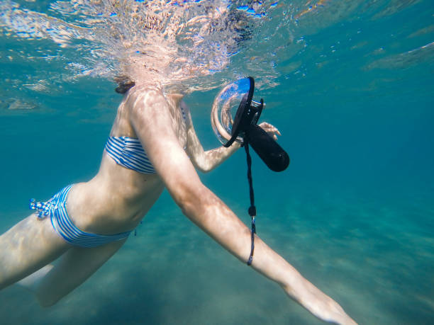 istock Woman swimming with action camera 694764652