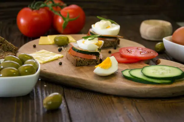 Delicious mini sandwiches with chrono bread, meat, pork, cheese, olives, tomato, rosemary, cucumber, peppercorns, salt, eggs and mayonnaise,