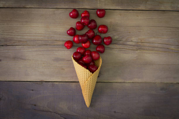 istock Cherries in cone on a wooden background 694767412