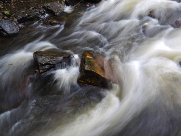 istock Strong current in river passing around rocks with long exposure 694782056
