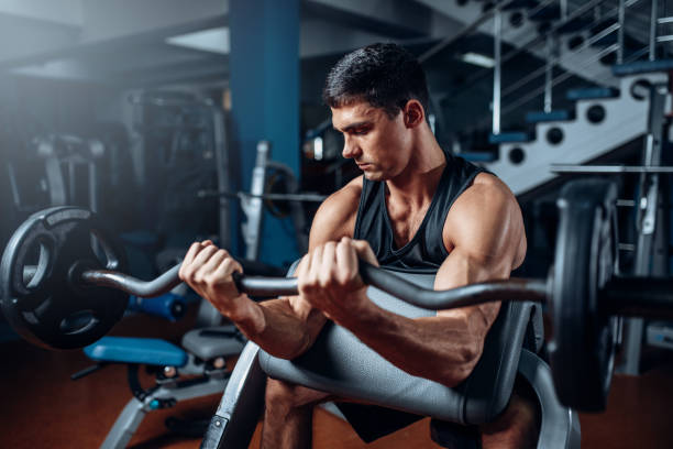 istock Tanned man exercise with barbell in gym 694782096