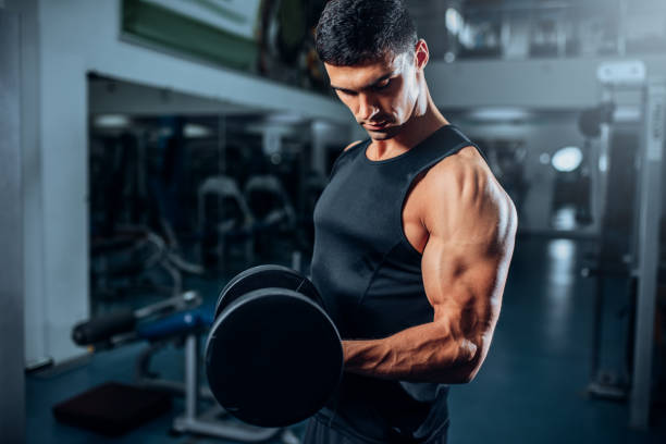 istock Tanned muscular athlete workout with dumbbell 694782402