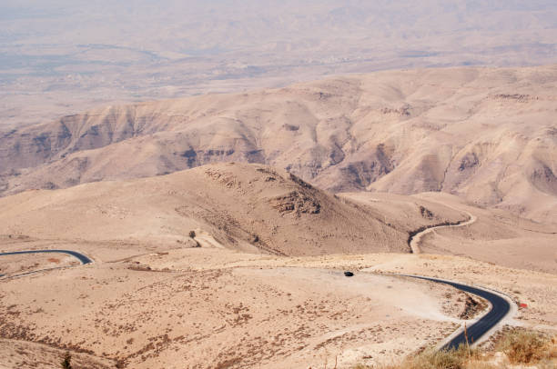 Jordan: the jordanian and desert landscape with the winding road to Mount Nebo, an elevated ridge mentioned in the Hebrew Bible as the place where Moses was granted a view of the Promised Land Mount Nebo, Jordan - September, 30, 2013: the jordanian and desert landscape with the winding road to Mount Nebo, an elevated ridge mentioned in the Hebrew Bible as the place where Moses was granted a view of the Promised Land mount nebo jordan stock pictures, royalty-free photos & images