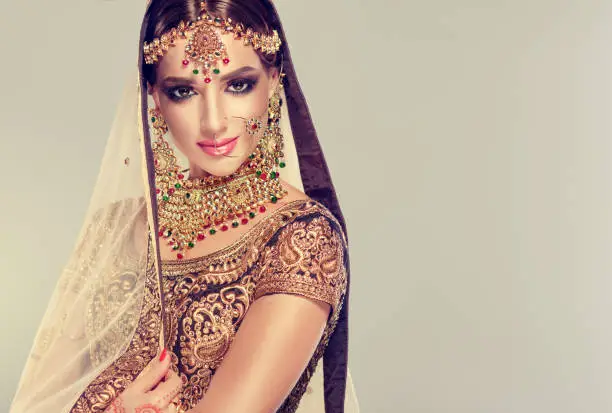 Photo of Young attractive model dressed in posh, gildet, indian costume and Kundan style jewelry.