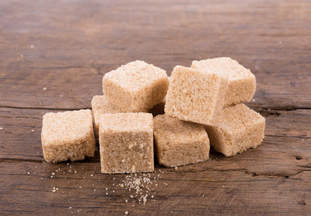 istock Brown cane sugar cubes on wooden background. top view 694808910