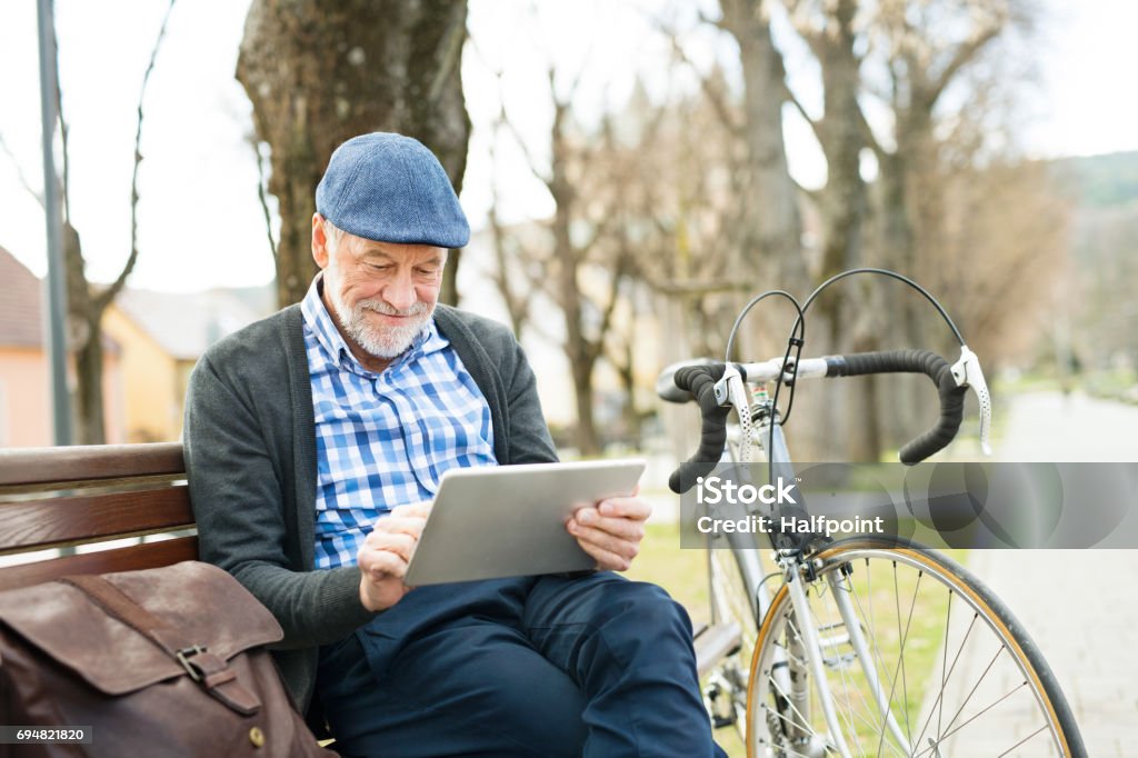 Senior hombre ciudad sentado en Banco, trabajo en tableta - Foto de stock de Leer libre de derechos