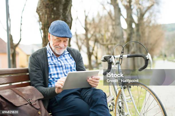 Senior Hombre Ciudad Sentado En Banco Trabajo En Tableta Foto de stock y más banco de imágenes de Leer