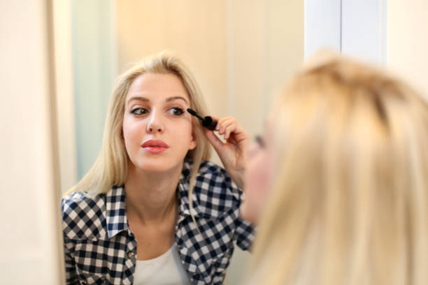 istock Blonde woman putting on mascara 694828152
