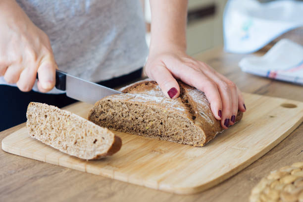 istock Young woman cutting freshly made bread 694834858
