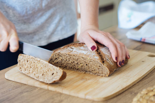istock Young woman cutting freshly made bread 694834870
